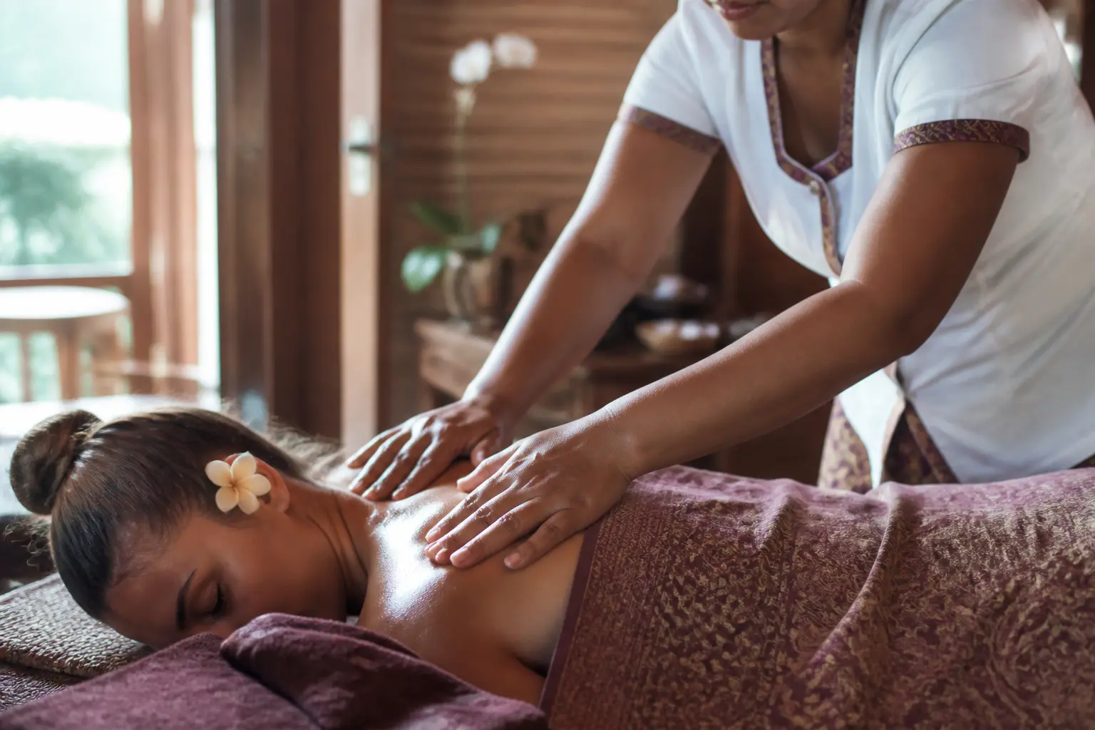 Massage balinais c'est quoi : thérapeute massant le dos et les épaules dans un spa balinais apaisant, lumière douce naturelle